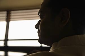 Profile view of young adult male Indian slihouetted near window.