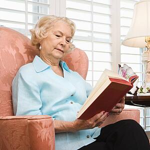 Mature Caucasian woman sitting in chair reading a book.