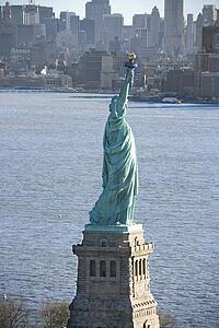 Aerial view of Statue of Liberty with Manhattan, New York buildings in background.