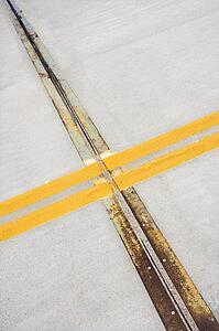 Detail of solid double yellow line in road crossing metal strips in cement.
