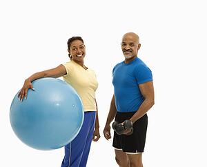 Woman holding blue exercise ball standing with man 