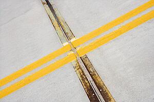 Detail of solid double yellow line in road crossing metal strips in cement.
