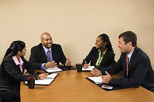 Businesspeople sitting at conference table smiling