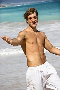 Attractive man walking on Maui, Hawaii beach smiling and reaching out