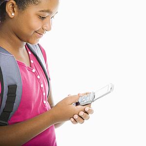 Girl with backpack text messaging on cell phone