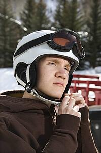 Caucasian male teenager fastening helmet.