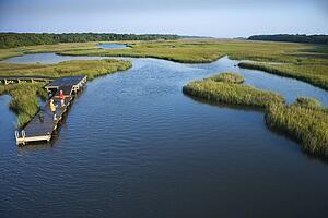 Aerial view of two teenage boys fishing from dock in marshy lowlands of Bald Head Island, North Carolina