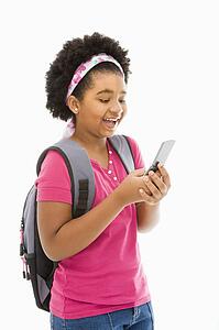 Girl with backpack text messaging on cell phone