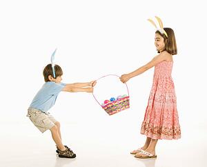 Boy and girl wearing bunny ears fighting over Easter basket.