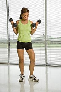 Woman standing lifting dumbbells