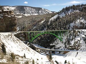 Mountain landscape with bridge crossing over roadway.
