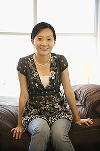 Portrait of female sitting on bed.