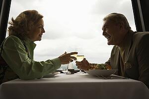 Caucasian mature couple at nice restaurant drinking wine and talking and laughing.