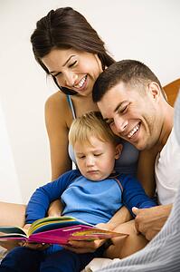 Caucasian parents and toddler son reading book.