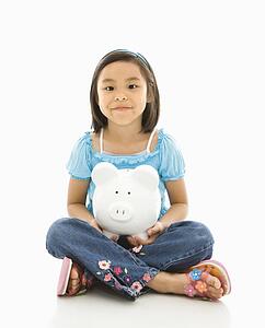 Girl sitting on floor holding piggybank