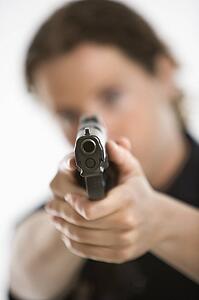 Close up of mid adult female Caucasian law enforcement officer aiming gun at viewer.