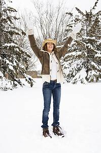 Female standing and playing in the snow wearing straw cowboy hat