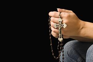 Woman holding rosary with crucifix.