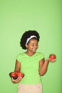 African American girl holding apples.