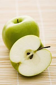 Still life of whole and sliced green apples.