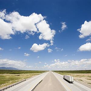 High angle view of highway with tractor trailer truck and blue cloudy sky.