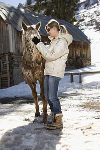 Woman petting horse with stable