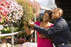 Happy smiling couple picking out flowers at outdoor plant market