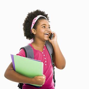 Girl with books and wearing backpack talking on cell phone
