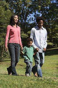 Parents and young son walking in park holding hands