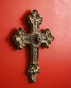 Ornate religious cross hanging on red wall
