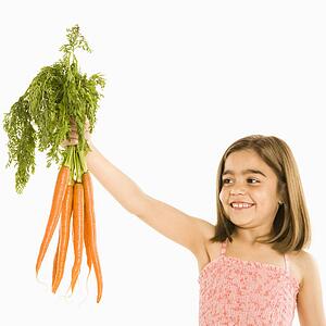 Smiling girl holding bunch of carrots 
