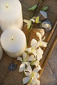 Above view of lit candles on tray with white orchid flowers.