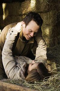Couple laying in hay embracing