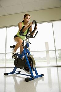 Woman pedaling exercise bicycle indoors