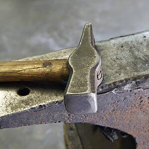 Still life shot of hammer laying on anvil.