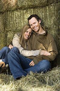 Couple sitting on hay hugging