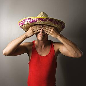 Portrait of a mid-adult Caucasian male wearing sombrero with hands over eyes.