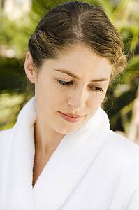 Attractive mid-adult woman in white robe looking down