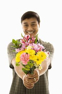 Man holding bouquet of flowers and smiling.