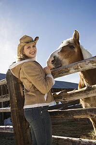 Woman standing at fence with horse 