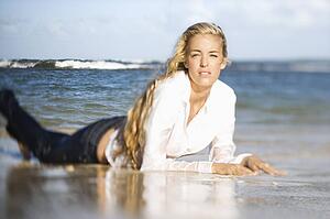 Portrait of pretty blond Caucasian woman lying on stomach on Maui, Hawaii beach.