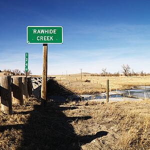 Rawhide creek sign in rural landscape.