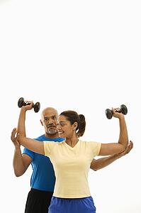 Man assisting woman with dumbbells
