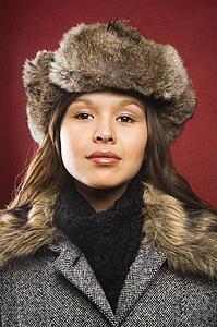 Young adult woman wearing fur hat looking at viewer.