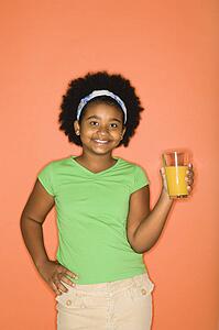 Girl with hand on hip holding glass of orange juice