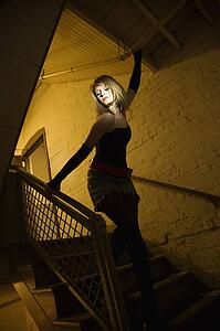 Caucasian female posing in stairwell with direct light on her face.