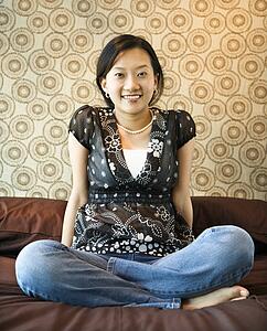 Portrait of woman sitting on bed looking at viewer.