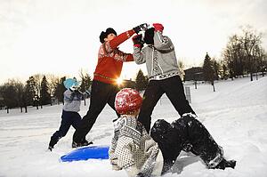 Caucasian family of four having fun playing in snow.