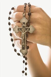Woman's hands holding rosary with crucifix