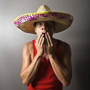 Portrait of a mid-adult male wearing sombrero with hands over mouth